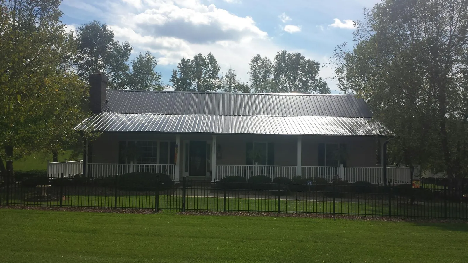Gray metal roof on a brick ranch with a full width front porch — Gutter Guard Installation work by our crew in West Harrison