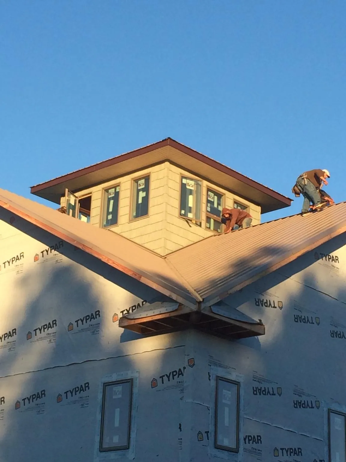 Roofers working around a rooftop cupola on a new metal roof at sunset — Roof Waterproofing in West Harrison by Roofing Brothers